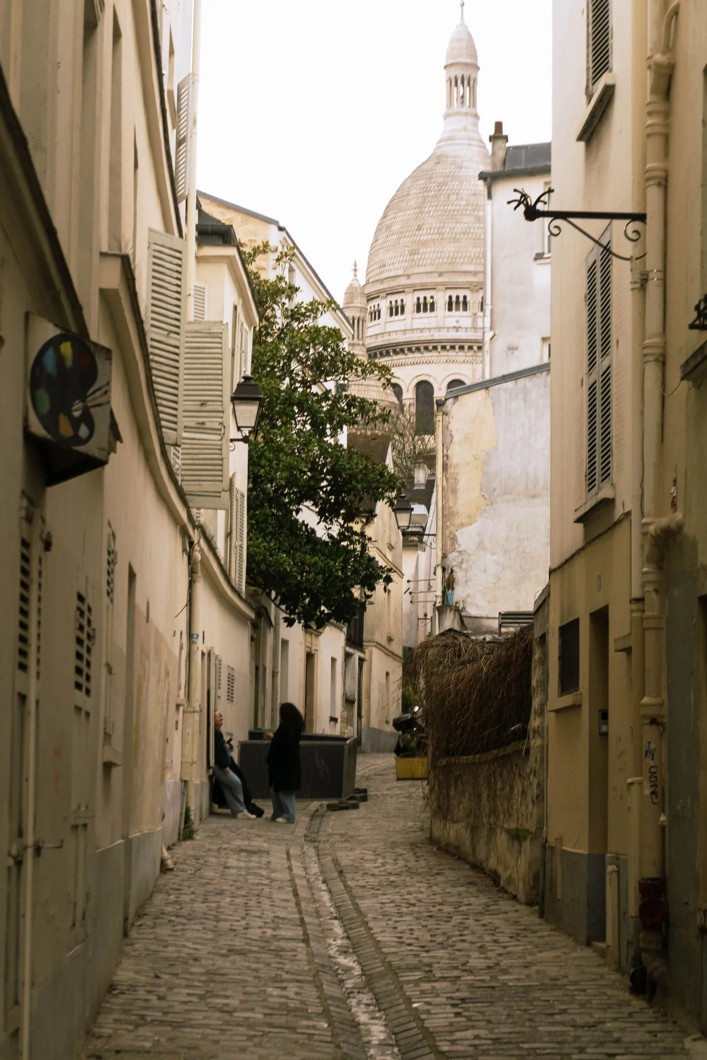 Rue pavée en pente de Montmartre avec vue sur le Sacré-Cœur — enlèvement d'épave moto et scooter dans le 18e arrondissement de Paris (75018)